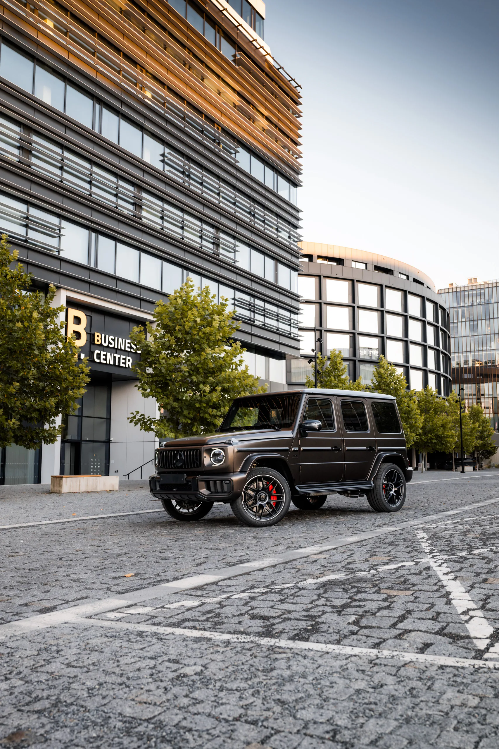 Mercedes-AMG G 63 in matte bronze parked between modern office buildings